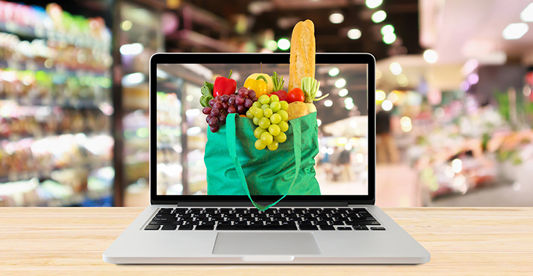 supermarket aisle blurred background with laptop computer and green shopping bag on wood table grocery online concept